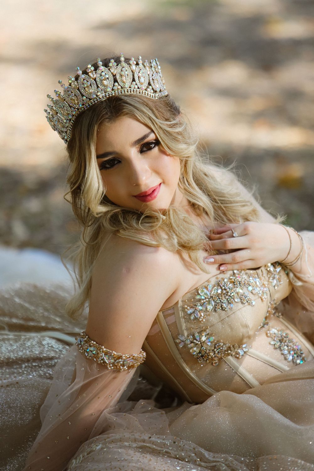 Close-up portrait highlighting an ornate crystal crown and champagne gown with detailed beadwork.