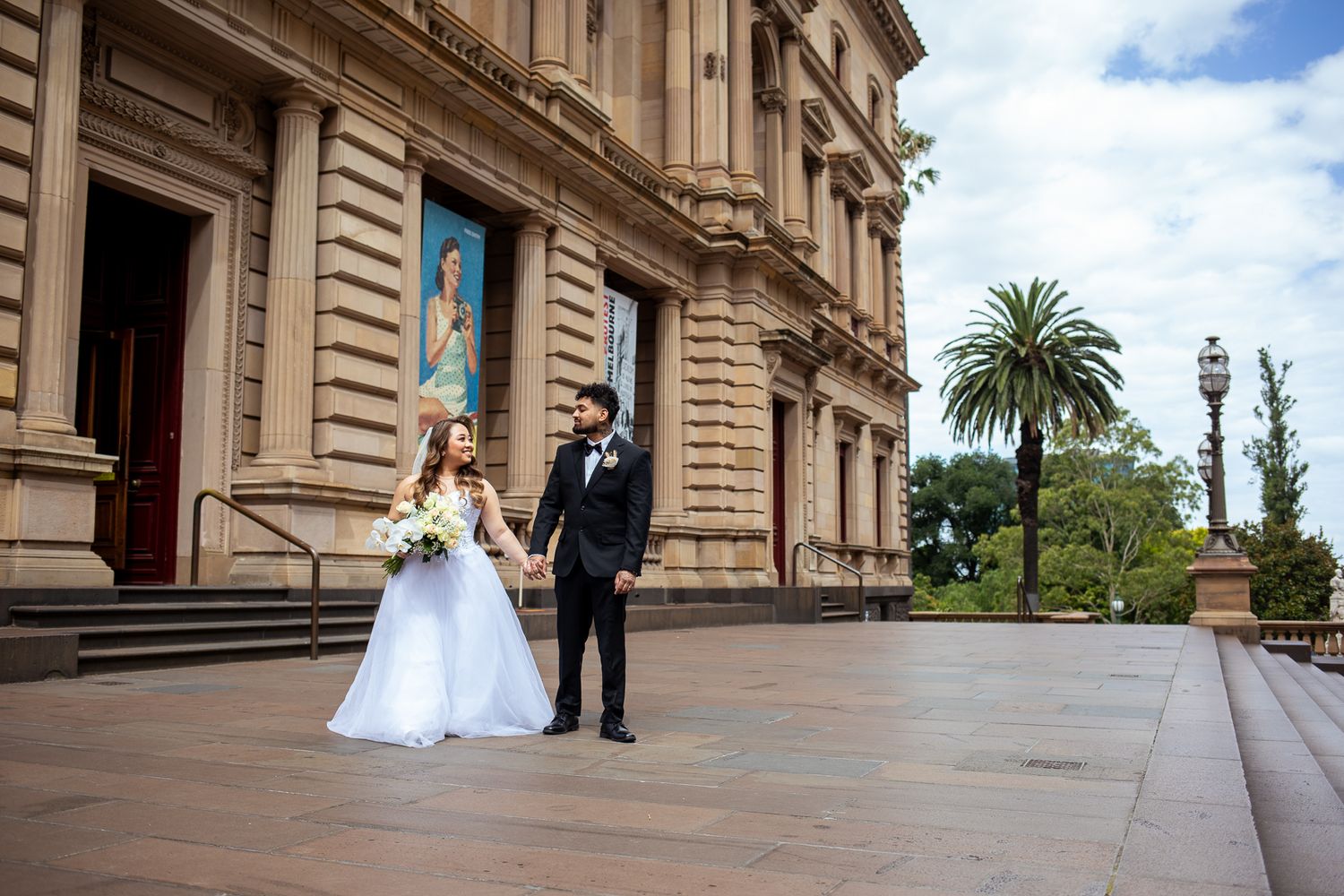Newlyweds holding hands outside Treasury Buildings, joyful Melbourne wedding photoshoot