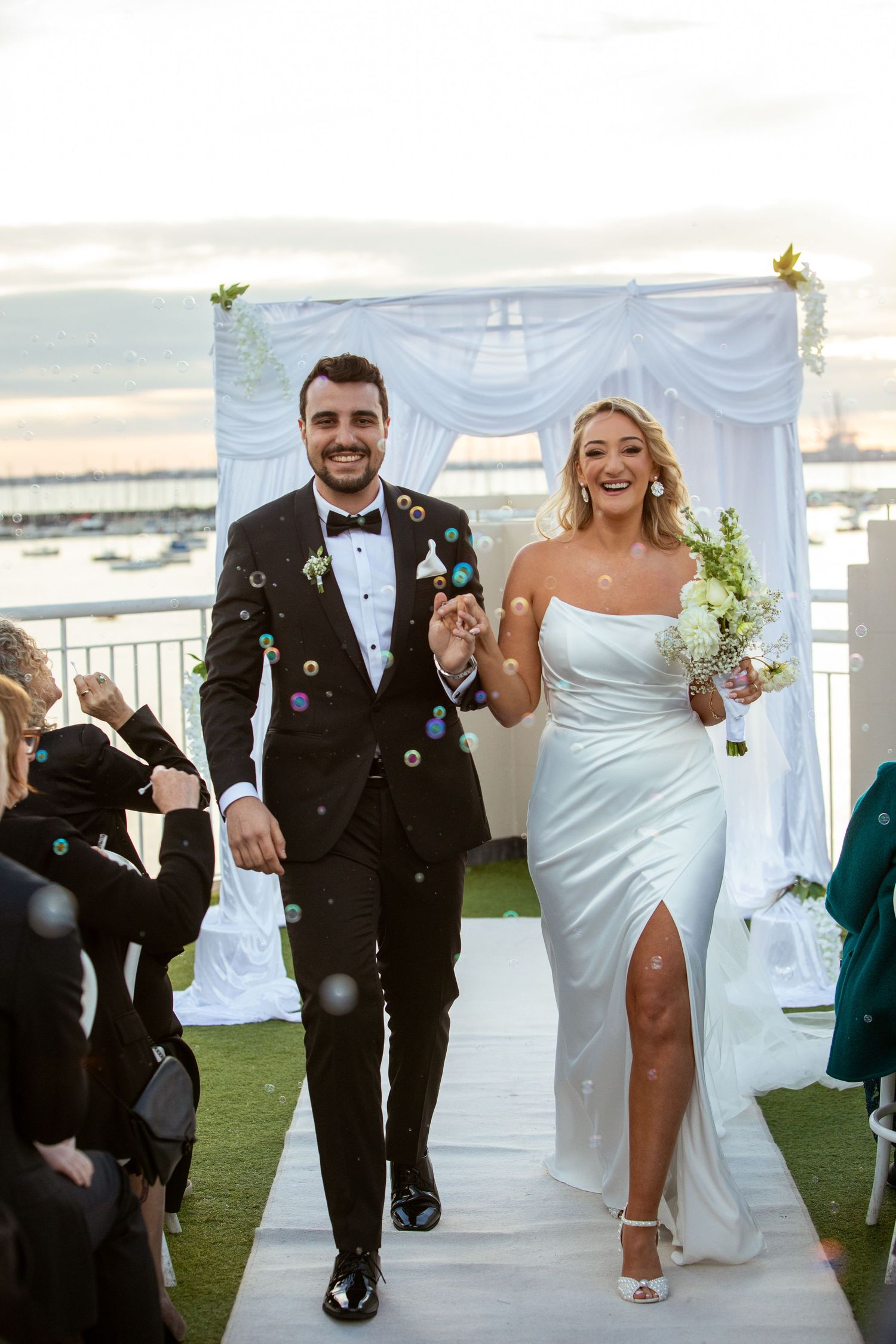 Melbourne wedding photographer captures a jubilant couple showered with bubbles as they exit their wedding ceremony.