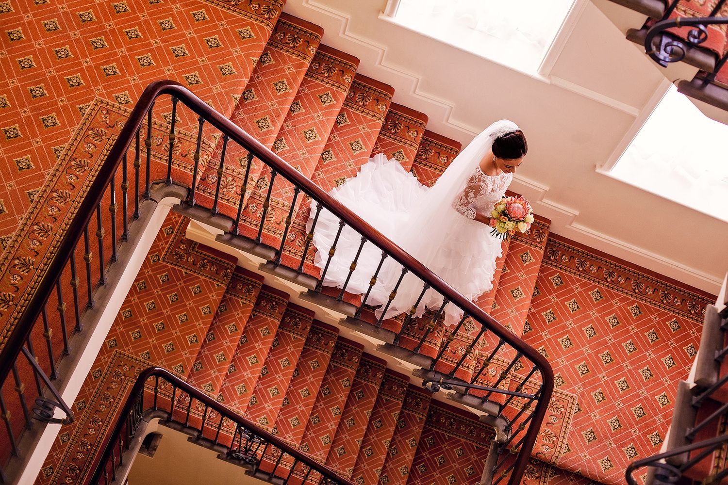 Melbourne wedding photographer captures a radiant bride in her wedding dress walking down a staircase towards her wedding