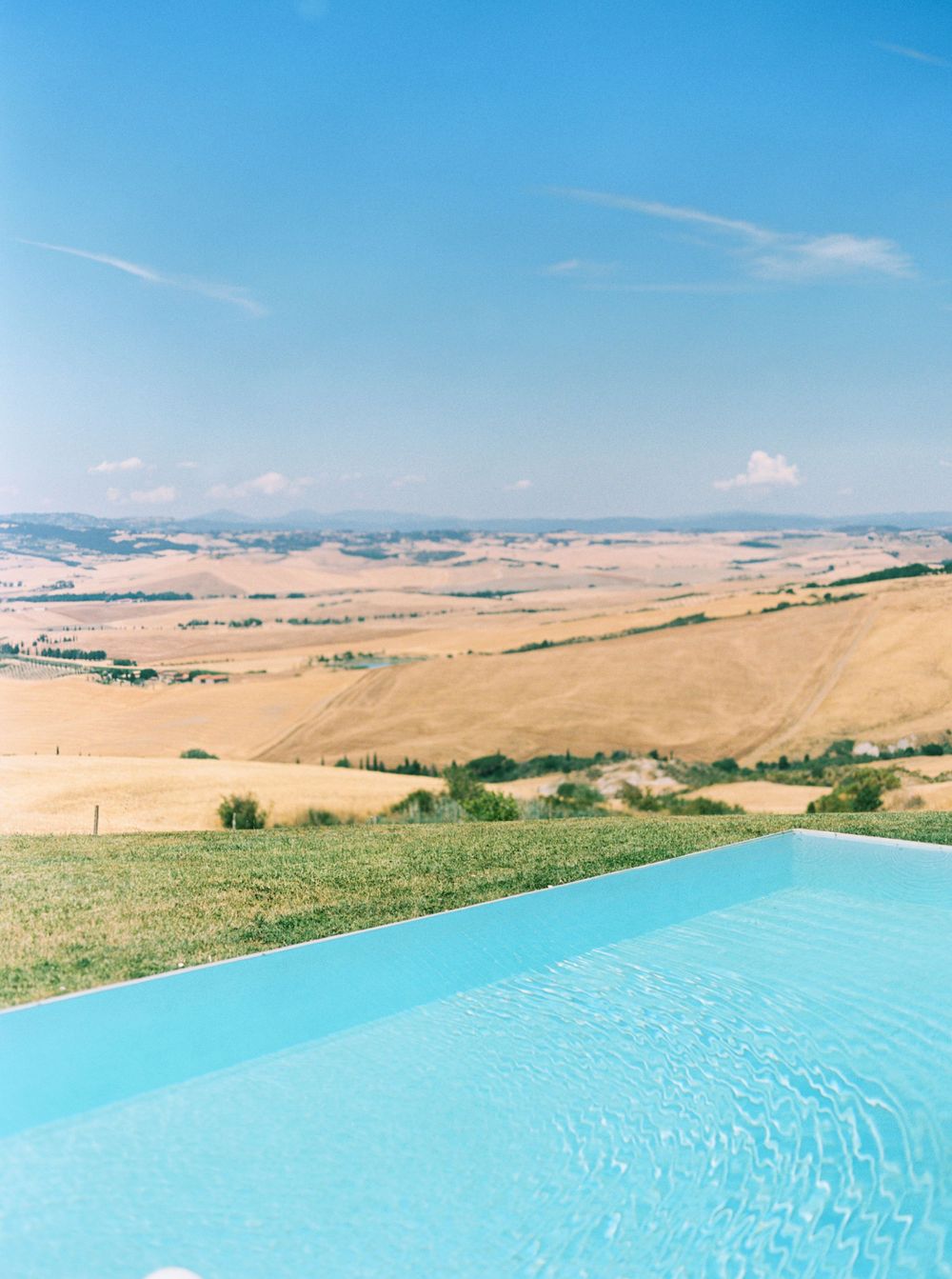 A serene pool overlooking a picturesque field at La Bandita Countryhouse in Tuscany, Italy.