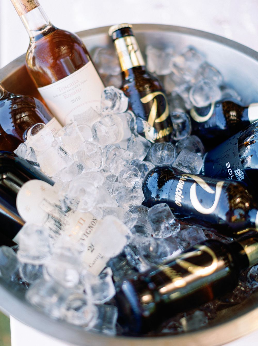 A bowl filled with wine bottles and ice, at a wedding pool party in Tuscany, Italy.