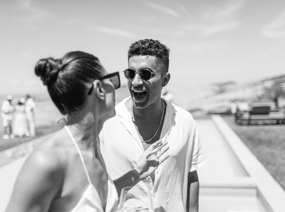 A couple laughing by a pool at a wedding pool party in Tuscany, Italy.