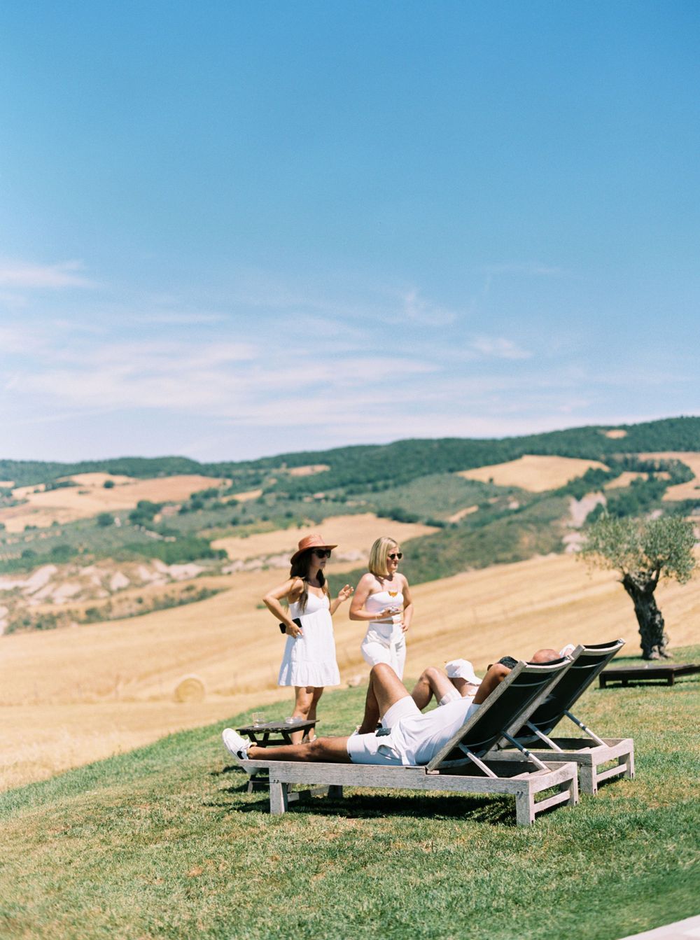 In Tuscany, Italy, a couples relaxing on a lawn chair, enjoying a wedding pool party.