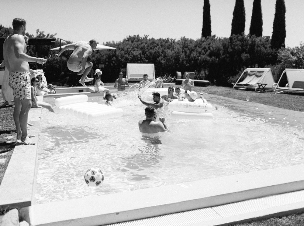 Black and white photo of individuals enjoying a pool in Tuscany, Italy.