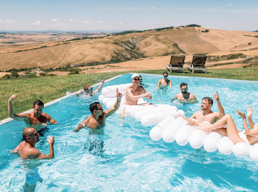 A lively scene at La Bandita Countryhouse in Tuscany, Italy: people enjoying a pool party with inflatable rafts.