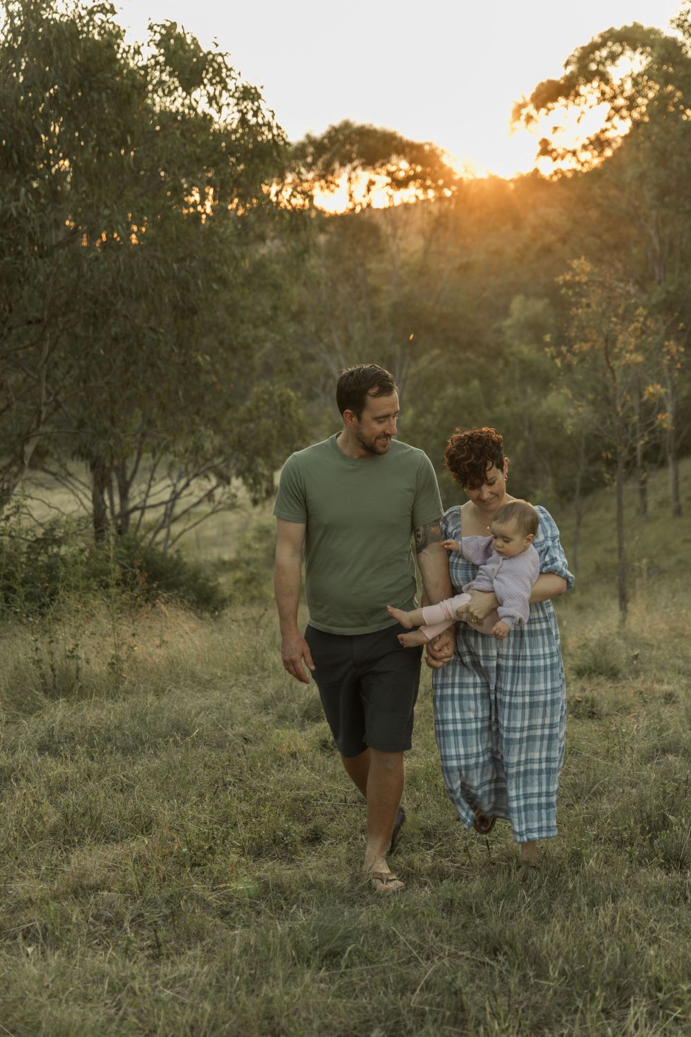 A family takes a peaceful stroll together through grassy fields at golden hour.