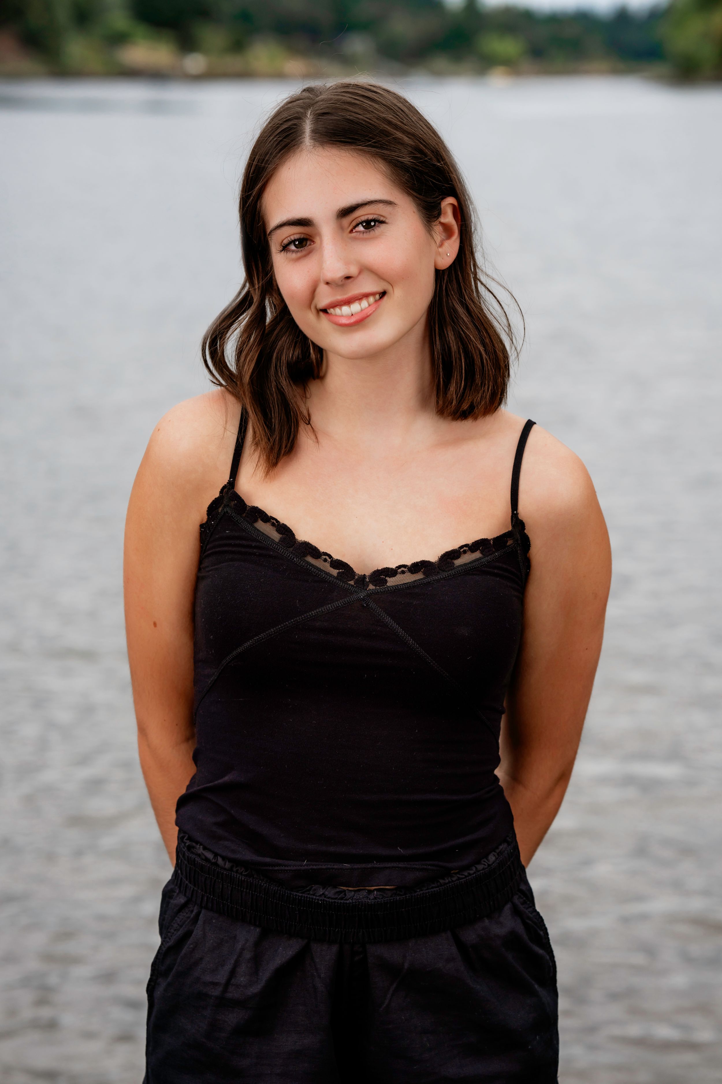 Lakeridge High School Dance Team Dancer in a black lace camisole poses by a lake on an overcast day.