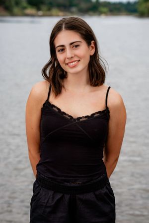 Lakeridge High School Dance Team Dancer in a black lace camisole poses by a lake on an overcast day.
