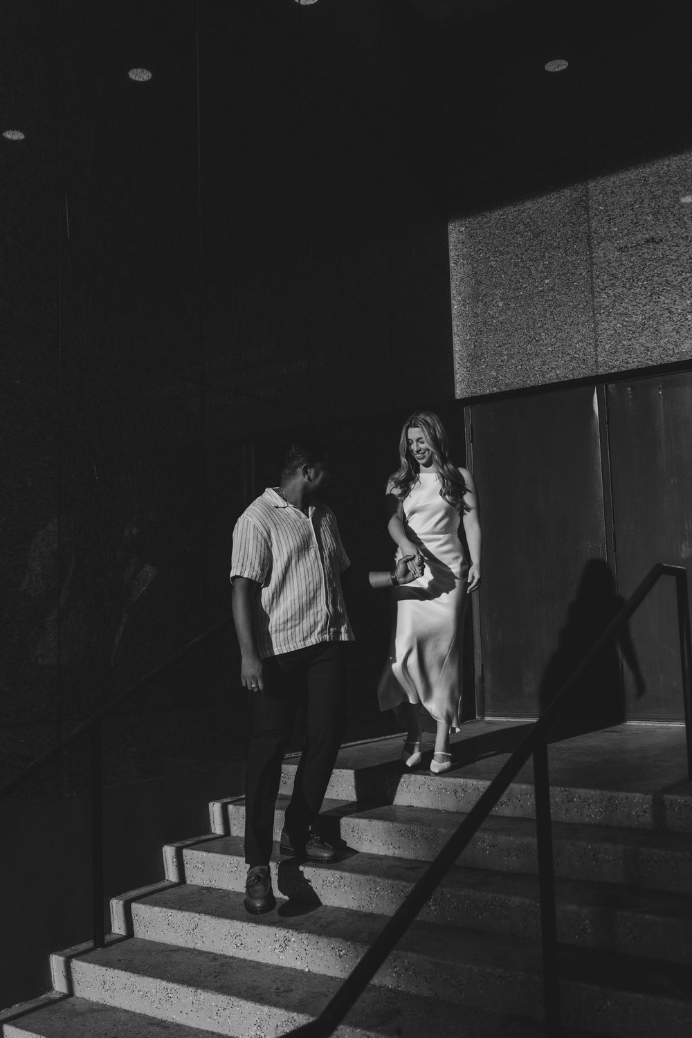 A black and white photo on stairs with dramatic lighting inside a building.
