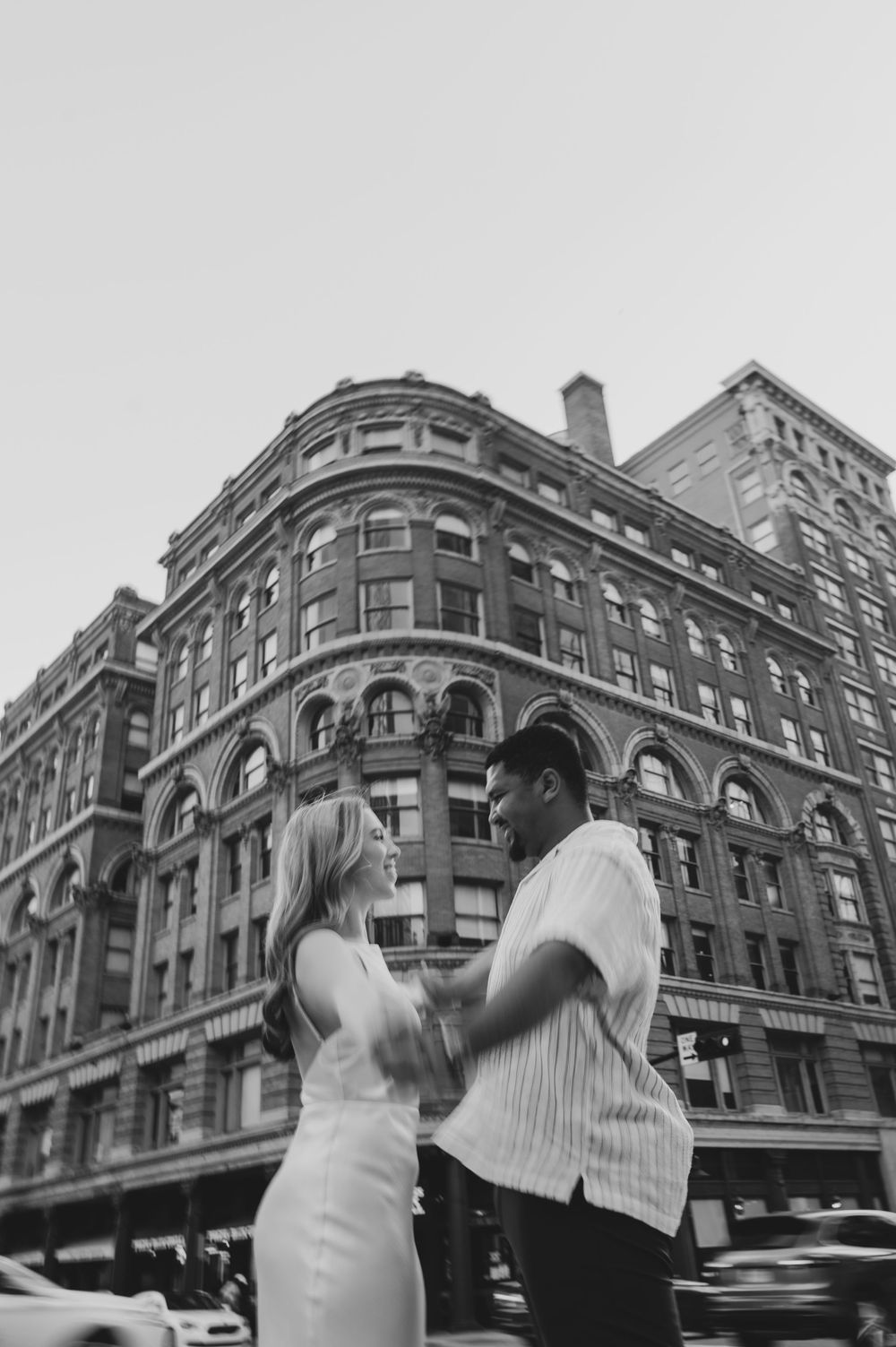 A romantic moment captured in black and white against the backdrop of an ornate historic building in the city.