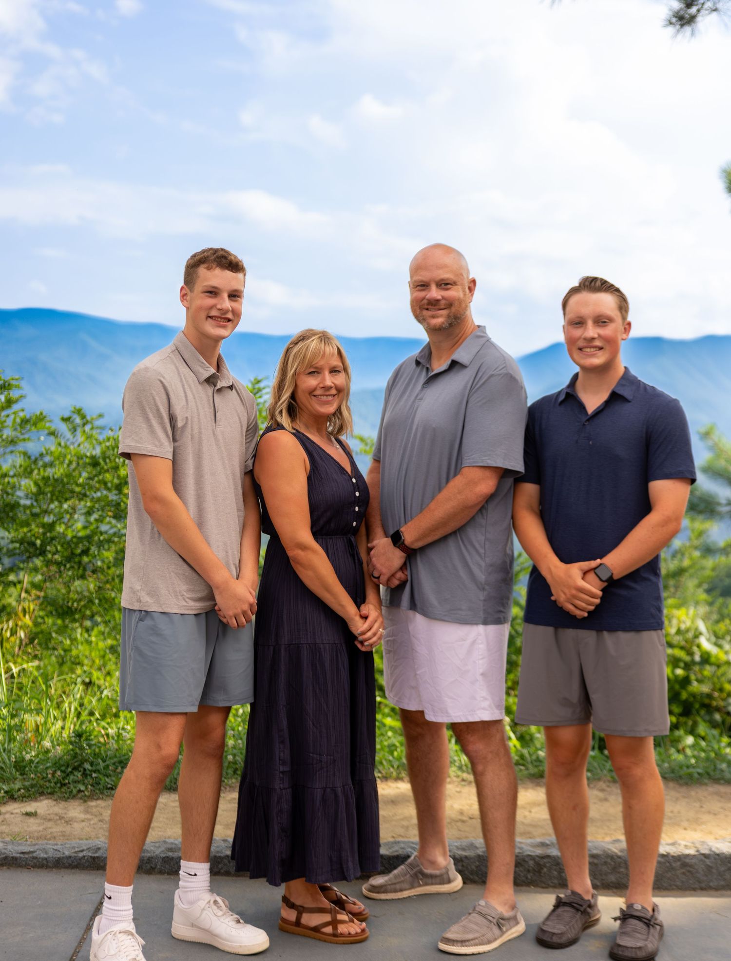 Family and white dog posing together on grass for outdoor portrait.
