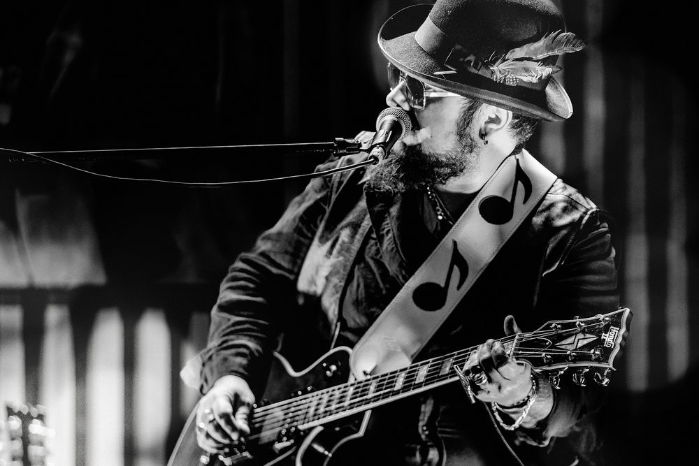 Black and white photograph of musicians performing on stage with guitars and instruments.