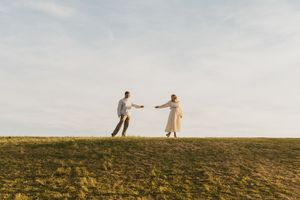 cinematic photo of couple waling on the top of green grass hill