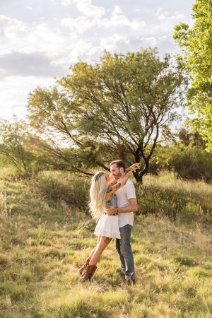A couple embraces joyfully on a grassy hillside during golden hour in Jacksonville North Carolina