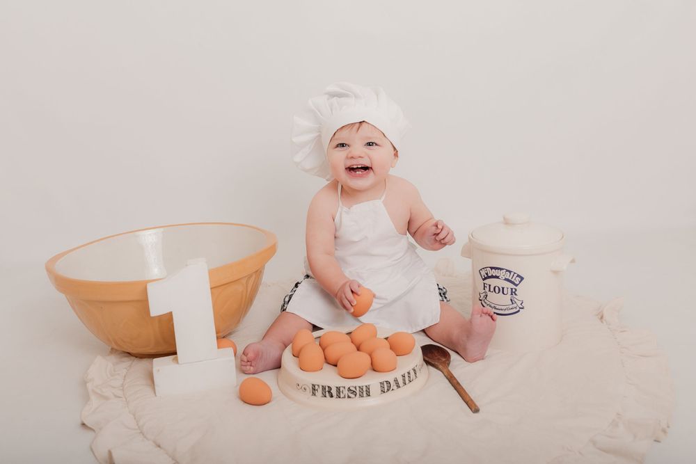 Baby in chef hat playing with eggs and mixing bowl on white background. Photographer. Hull. East Yorkshire. Photography