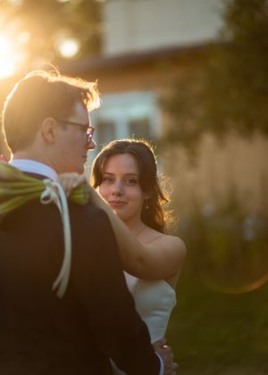 Couple sharing a romantic golden hour moment outdoors, bride in white dress gazing lovingly at groom in tuxedo.