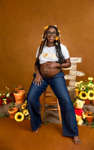 A maternity photo featuring sunflowers, rustic decor, and a cozy autumn setting with a warm brown background.