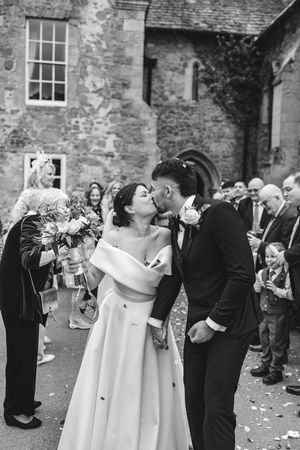 Wedding party and guests celebrating with champagne toasts outside a historic stone building.
