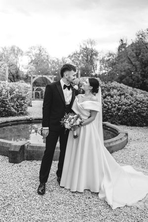 A bride and groom share an intimate moment in a garden setting on their wedding day.