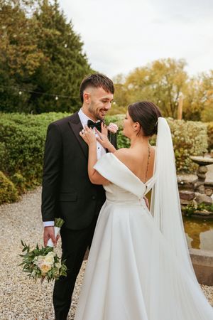 Newlyweds share a joyful moment together on their wedding day in a garden setting with autumn foliage.