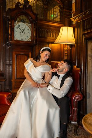 A playful wedding moment captured in an elegant wood-paneled room with warm lighting and vintage decor.