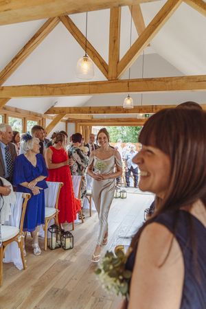Wedding guests dance and celebrate in a rustic barn venue with wooden beams and warm lighting.