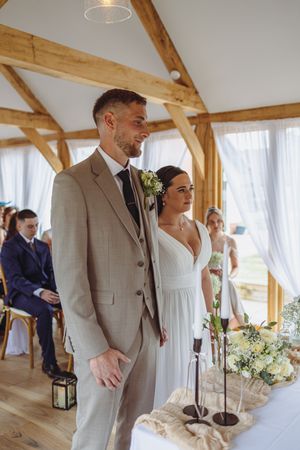 Newlyweds celebrate during their rustic barn wedding reception with elegant white curtains and wooden beams.