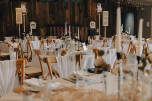 Elegant wedding reception venue with white table linens, candlesticks and warm lighting creating a romantic atmosphere.