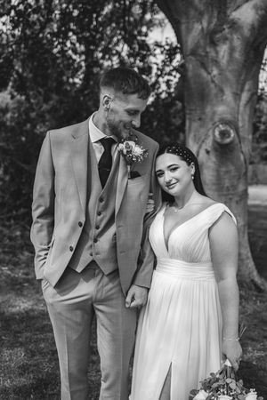 Wedding couple in black and white sharing an intimate moment among trees in a garden setting.