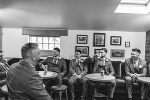 A group of people in formal attire gathered around tables for conversation in a black and white photograph.
