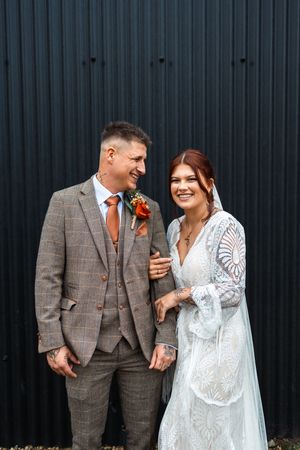 A couple in wedding attire share candid laughing moments against a dark wall in a four-photo sequence.