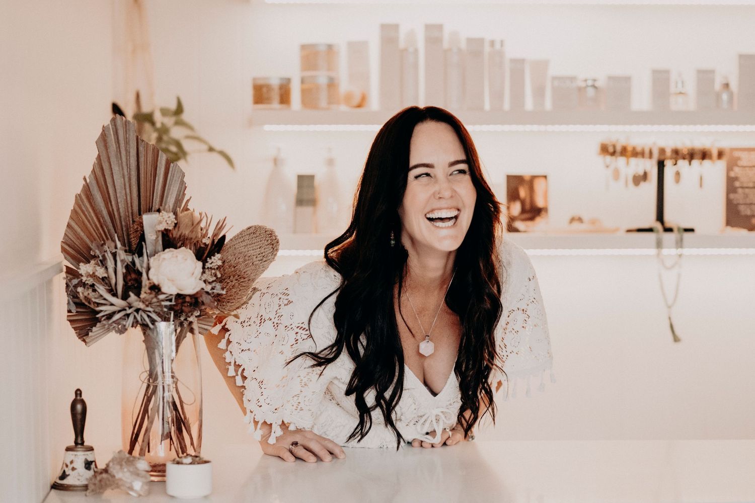 Professional smiling in bright modern space with shelves and decor visible behind them.