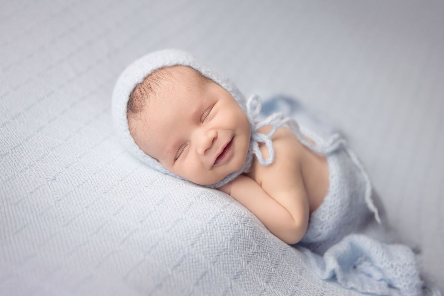 Peaceful newborn portrait with purple knit bonnet on textured lavender backdrop.