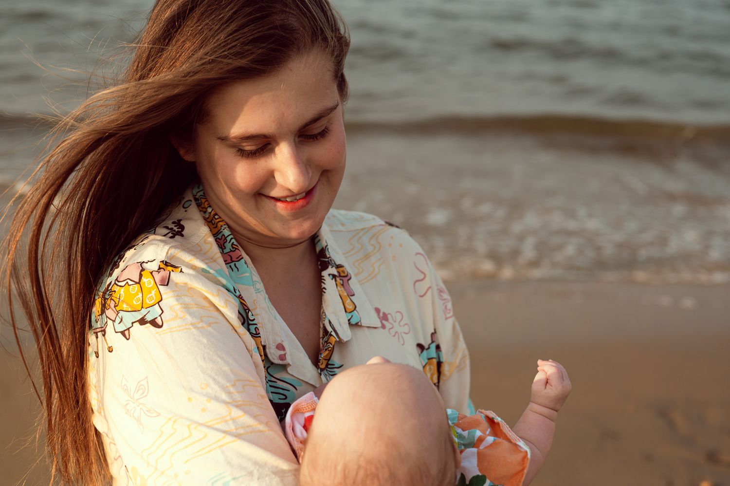 A mother and daughter share tender moments together while playing on a sandy beach at sunset.