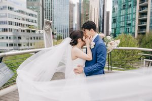Modern urban wedding photo with city skyline and glass buildings in background.