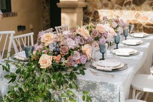 Elegant wedding reception table with peach and pink floral centerpieces and fine china place settings.