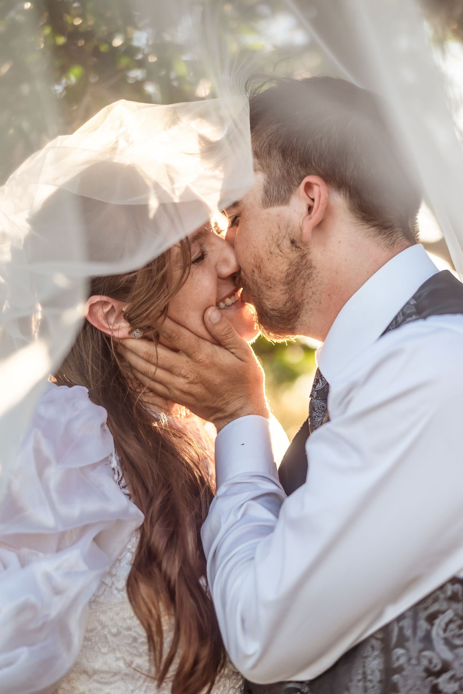 A romantic wedding moment captured in dreamy sunlit atmosphere with flowing veil.