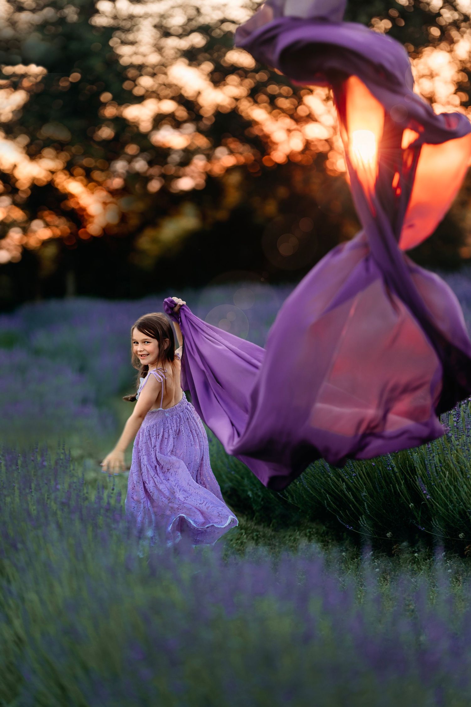 Flowing purple dress billows in the breeze among blooming lavender fields at sunset. Middle Tennessee Child Photographer