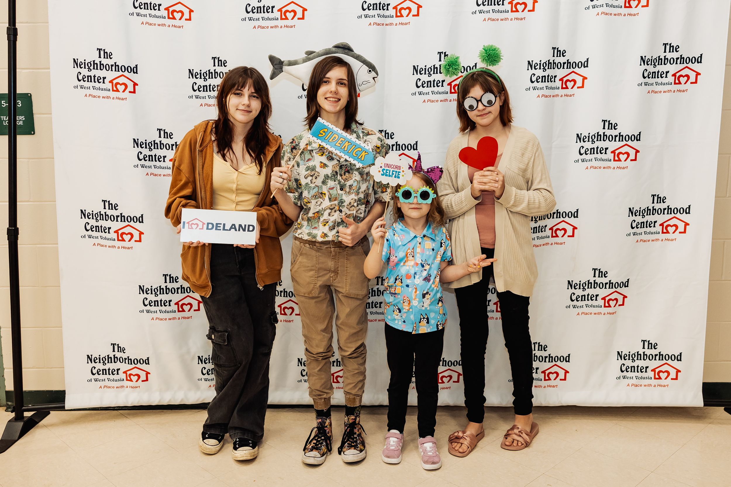 Family group posing in front of event backdrop with donations.