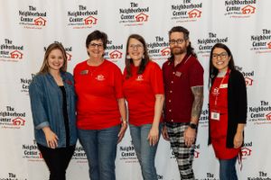 Five staff members in matching uniforms standing against branded backdrop.