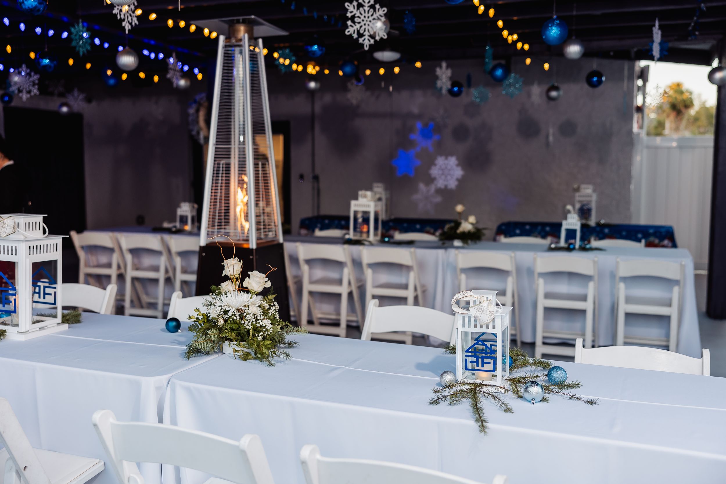 Winter themed event space with white chairs, string lights and snowflake decorations.