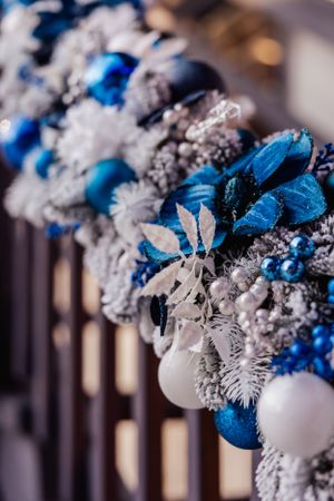 Close up of blue and white Christmas ornaments and frosted decorations on garland.