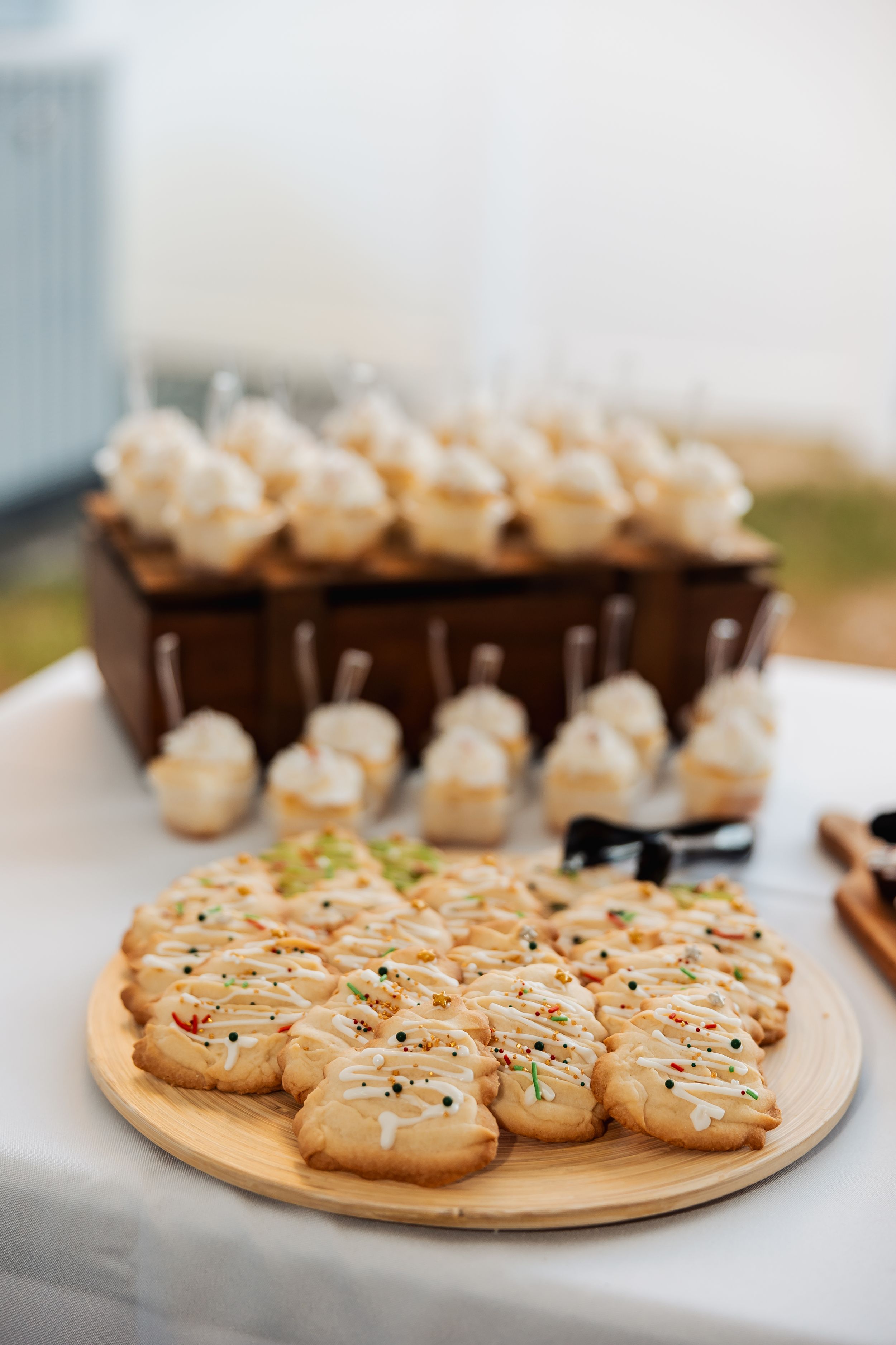 Decorated cookies and dessert bites displayed on wooden plates for catering event.