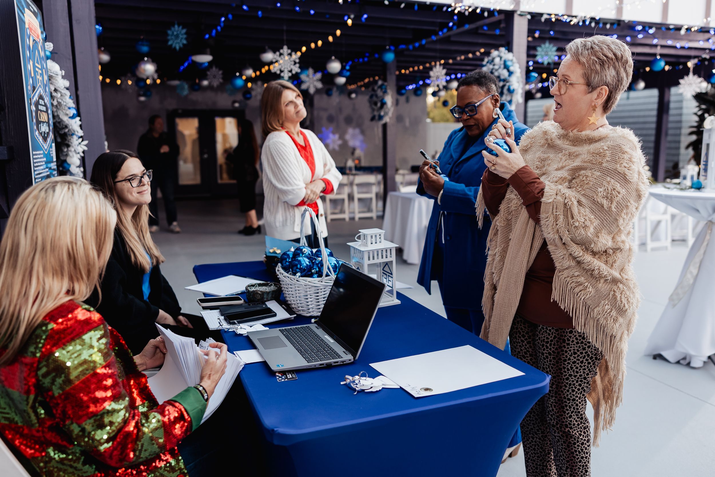 Group meeting at decorated event space with holiday decor and blue tablecloths.