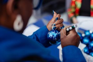 Close-up of hands decorating with blue Christmas ornaments and holiday decor.
