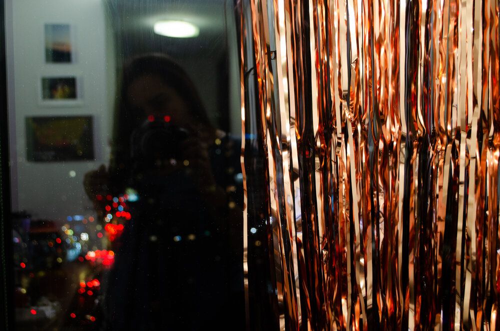 Glowing copper metallic tinsel decoration in dark room with lights in background.