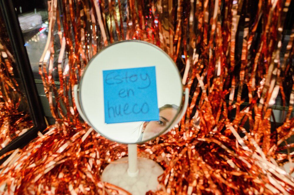 Round mirror surrounded by copper colored tinsel with blue sticky note.