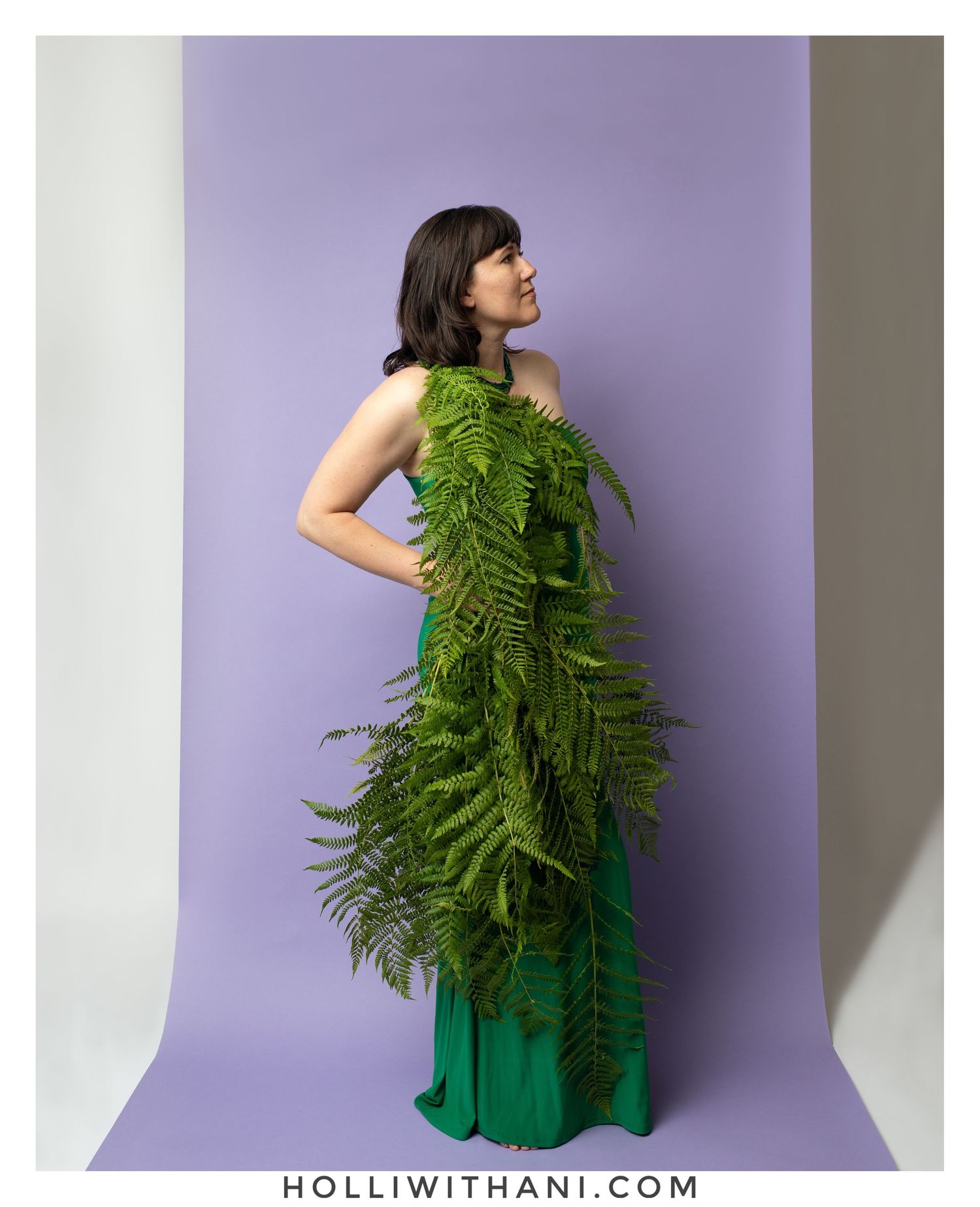 Color portrait of woman in green fern dress on purple background.