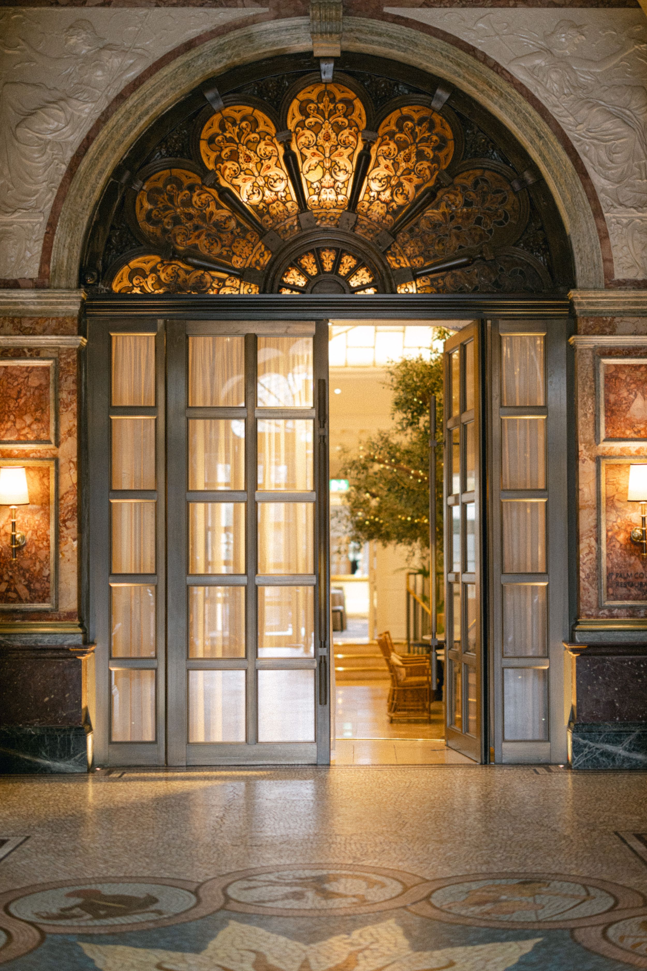 Ornate arched doorway with illuminated fan design and wooden double doors in classical architecture.